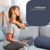 A woman is sitting on a couch and holding her neck in pain. A blue bolster pillow is on the couch next to her. Podgląd zdjęcia produktu