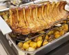 A roasted rack of ribs with potatoes in a roasting pan. Produktbild-Vorschau