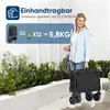 A woman is holding a folded black wagon, with text overlays indicating its features and weight. Produktbild-Vorschau