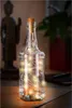 A clear glass bottle filled with fairy lights and corked, sitting on a wooden surface with a statue and a plant in the background. Anteprima dell’immagine prodotto