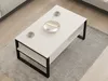 A white coffee table with black legs is placed on a gray rug in a living room setting. Produktbild-Vorschau