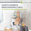 A woman is holding a basket of laundry next to a washing machine, with a laundry basket in the foreground. Náhľad obrázku produktu