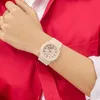 A close-up shot of a person's wrist wearing a beige watch, with a red shirt in the background. Podgląd zdjęcia produktu