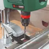 A close-up shot of a Bosch drill press with a laser guide, drilling into a metal beam. Podgląd zdjęcia produktu