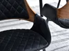 Close-up of two black upholstered chairs with wooden accents. Náhled obrázku produktu