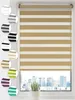A close-up view of a beige and white striped roller blind hanging in a window, with a city skyline visible outside. Produktbild-Vorschau