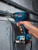 A hand holding a Bosch impact driver, using it to screw into a metal pipe mounted on a concrete wall. Anteprima dell’immagine prodotto