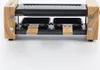 A close-up, front-facing view of a raclette grill with wooden accents, set against a plain white background. Produktbild-Vorschau