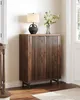 A dark wood cabinet with slatted doors stands in a hallway, topped with a lamp and a vase of flowers. Náhľad obrázku produktu