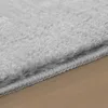 Close-up of the edge of a soft, silver-gray rug on a wooden floor. Produktbild-Vorschau