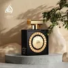 A black perfume bottle with gold accents is displayed on a gray pedestal, with greenery and soft lighting. Podgląd zdjęcia produktu
