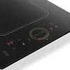 A close-up, angled view of a black induction cooktop with gold accents and a digital display. Podgląd zdjęcia produktu