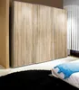 A bedroom scene with a large wardrobe and a bed with a blue blanket. Produktbild-Vorschau