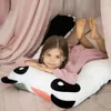 A young girl is lying on a bed with a panda pillow. Náhľad obrázku produktu