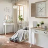 A bedroom scene with a vanity, bed, and clock. Produktbild-Vorschau