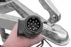 A hand holding a trailer connector plug in front of a trailer hitch. Produktbild-Vorschau