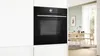 A modern kitchen with a built-in Bosch oven and a dining area in the background. Produktbild-Vorschau