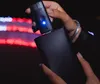 A person is holding a black electronic device with a blue light, connecting it to a larger black device. Náhled obrázku produktu
