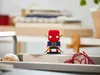 A LEGO BrickHeadz Iron Man figure is displayed on a desk with books and office supplies in the background. Produktbild-Vorschau