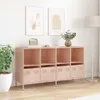 A pink storage cabinet with multiple compartments and drawers, placed against a white wall with two framed abstract art pieces above it. A floor lamp stands to the right, and a potted plant is to the left. Produktbild-Vorschau