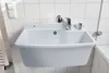 A white sink with a chrome faucet and soap dispenser mounted on a tiled wall. Produktbild-Vorschau