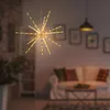 A starburst-shaped LED light fixture hangs in a living room, casting a warm glow. Produktbild-Vorschau