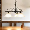 A chandelier with three lights hangs above a wooden table. Produktbild-Vorschau