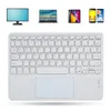 A white wireless Bluetooth keyboard with a touchpad is shown against a white background, with images of a monitor, laptop, tablet, and smartphones displayed above it. Náhľad obrázku produktu