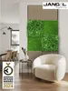A modern living room with a modular wall panel featuring moss and artificial plants, a round armchair, and a side table. Produktbild-Vorschau