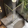 A modern bathroom with a gold-framed shower enclosure, a rain showerhead, and lush indoor plants visible through the glass. Produktbild-Vorschau