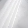 A close-up view of white, translucent fabric with pleats and a textured weave. Produktbild-Vorschau
