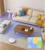 A clean and modern living room with a sofa, coffee table, and a robot vacuum cleaner. Produktbild-Vorschau
