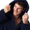 A man wearing a navy blue hooded robe, holding the hood with his hands and smiling. Produktbild-Vorschau