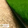 A close-up view of a black edging strip separating gravel from grass. Produktbild-Vorschau