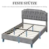 A grey upholstered bed frame with a tufted headboard, shown from a diagonal angle, highlighting its support structure. Produktbild-Vorschau