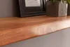 A close-up view of a wooden shelf with a natural edge, showing the wood grain and texture. A framed picture and a potted plant are visible in the background. Anteprima dell’immagine prodotto