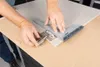 A person is using a measuring tool to mark a cabinet door for hinge installation. Voir les images du produit