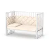 A white baby crib with a beige mattress and bumper pad, shown against a white background. Anteprima dell’immagine prodotto