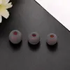 Three gray silicone ear tips with red inner cores are arranged on a black surface with a white diagonal element in the background. Voir les images du produit