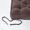 A close-up view of a brown tufted seat cushion with ties. Náhled obrázku produktu