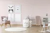 A nursery room with a crib, rocking horse, armchair, and wall art. Produktbild-Vorschau