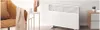 A white Xiaomi smart space heater is shown in a modern living room setting next to a side table with a decorative cactus and a cup, and a chair with a blanket draped over it. Produktbild-Vorschau
