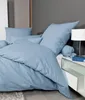 A neatly made bed with blue bedding and pillows. Produktbild-Vorschau