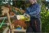 A person is using a cordless chainsaw to cut a log in an outdoor setting. Produktbild-Vorschau