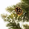 A close-up view of a decorated artificial Christmas tree branch with a pinecone and artificial snow. Voir les images du produit