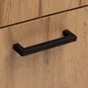 A close-up of a black handle on a wooden cabinet. Náhled obrázku produktu