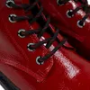 Close-up of red patent leather boots with black and red laces. Produktbild-Vorschau