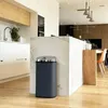 A modern kitchen with a trash can placed next to a marble island. Anteprima dell’immagine prodotto
