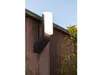 An outdoor wall lamp mounted on a wooden fence, with some greenery in the foreground and a clear blue sky in the background. Produktbild-Vorschau