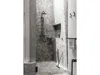 A modern bathroom with a marble-tiled shower and a black shower squeegee leaning against the wall. Produktbild-Vorschau